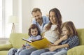 Happy family sitting on couch at home, looking through photo album or reading book Royalty Free Stock Photo