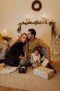 Happy family sitting on the floor with gifts and Christmas decoration in the background. Royalty Free Stock Photo