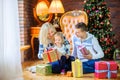 Happy family sitting on the floor near the Christmas tree congratulates and gives each other presents Royalty Free Stock Photo