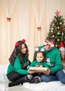 Happy family sitting in front a christmas tree and holding a gift Royalty Free Stock Photo