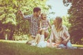 Happy family sitting on grass in the meadow together and enjoying in summer day. Royalty Free Stock Photo