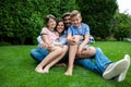 Happy family sitting on grass in park on a sunny day Royalty Free Stock Photo