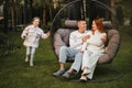 A happy family is sitting in a hammock on the lawn near the house Royalty Free Stock Photo