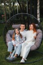 A happy family is sitting in a hammock on the lawn near the house Royalty Free Stock Photo