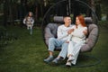 A happy family is sitting in a hammock on the lawn near the house Royalty Free Stock Photo