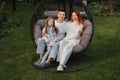 A happy family is sitting in a hammock on the lawn near the house Royalty Free Stock Photo