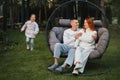 A happy family is sitting in a hammock on the lawn near the house Royalty Free Stock Photo