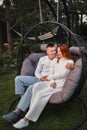 A happy family is sitting in a hammock on the lawn near the house Royalty Free Stock Photo