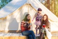 Happy family sitting near canvas bell tent outdoors during sunset Royalty Free Stock Photo