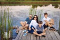 Happy family sitting on a pier on a lake or pond, relaxing in nature Royalty Free Stock Photo