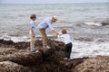 Happy family sitting on rock and watching ocean Royalty Free Stock Photo