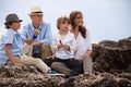 Happy family sitting on rock and watching ocean Royalty Free Stock Photo