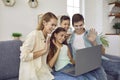 Happy family sitting on the sofa at home, making a video call and waving hello at their laptop Royalty Free Stock Photo