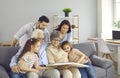 Happy family sitting on a sofa, reading a book or looking through a photo album together Royalty Free Stock Photo