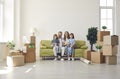 Happy family sitting on sofa in their new house or apartment full of unpacked boxes Royalty Free Stock Photo