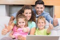 Happy family sitting on sofa using laptop giving thumbs up Royalty Free Stock Photo