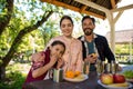 Happy Family Are Sitting By The Table In The Park. Plates With Different Fruits And Glasses With Water Are On The Table. Royalty Free Stock Photo