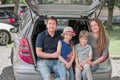 Happy family sitting in the trunk of a family car Royalty Free Stock Photo