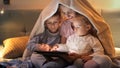 Happy family sitting under blanket and using tablet computer at night. Family having time together, parenting, happy childhood and Royalty Free Stock Photo