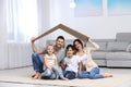 Happy family sitting under cardboard roof. Insurance concept