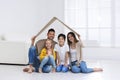 Happy family sitting under cardboard roof . Insurance concept