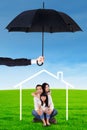 Happy family sitting under house icon and umbrella Royalty Free Stock Photo