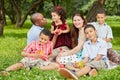 Happy family of six sits on rag matting and eats