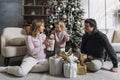 Happy family with a small child by the New Year tree with gifts. Festive mood, love and tenderness