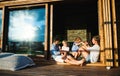 Family with small children sitting on patio of wooden cabin, holiday in nature concept. Royalty Free Stock Photo