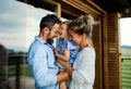 Family with small daughter standing on patio of wooden cabin, holiday in nature concept. Royalty Free Stock Photo