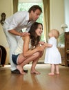 Happy family smiling at baby standing at home