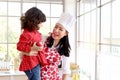 Happy family, smiling beautiful Asian mother wears cute red heart apron and chef hat holds daughter while little girl holds apple Royalty Free Stock Photo