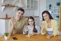 A happy family waving hands up looking at camera sitting at kitchen home