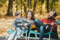 Happy family with son relaxing in autumn city park. Father playing the guitar Royalty Free Stock Photo