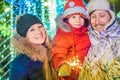 A happy family with sparklers near giant fir tree and Christmas illumination on Christmas market. Xmas holidays on fair Royalty Free Stock Photo