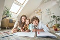 Young mother lying on the floor in the living room with teenage son and preschool daughter and smiling at camera, they Royalty Free Stock Photo