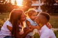 Happy family spending time outdoors walking in park. Mother and her son hugging little toddler girl and talking Royalty Free Stock Photo