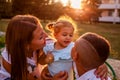 Happy family spending time outdoors walking in park. Mother and her son hugging little toddler girl and talking Royalty Free Stock Photo