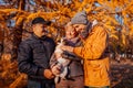 Happy family spending time with pug dog in autumn park. Parents with their son hugging pet. Family values Royalty Free Stock Photo