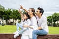 Happy family spending time together in the park, Beautiful asian family sitting on a chair in the park, pointing at something and Royalty Free Stock Photo