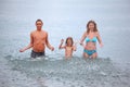 Happy family splashes water hands standing in sea