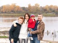 Happy family is standing near the river in the autumn day. Royalty Free Stock Photo