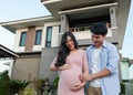 Happy family standing outside house and looking belly, husband and pregnant wife