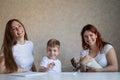 Happy family stays at home. Two women help the boy do school homework. Lesbian couple sitting at the table with their Royalty Free Stock Photo