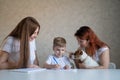 Happy family stays at home. Two women help the boy do school homework. Lesbian couple sitting at the table with their Royalty Free Stock Photo