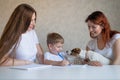 Happy family stays at home. Two women help the boy do school homework. Lesbian couple sitting at the table with their Royalty Free Stock Photo