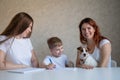 Happy family stays at home. Two women help the boy do school homework. Lesbian couple sitting at the table with their Royalty Free Stock Photo