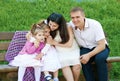 Happy family in summer city park outdoor, pregnant woman, parent and children, bright sunny day and green grass, beautiful people Royalty Free Stock Photo