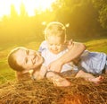Happy family in summer nature. Mother and baby daughter on hay