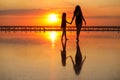 Happy family summer travel holiday. Silhouette of mom with child daughter holding hands walking together on beach on Royalty Free Stock Photo